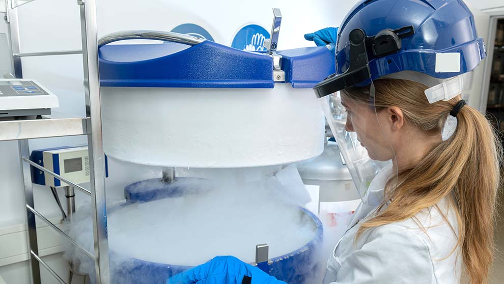 lab worker in full protective gear opens foggy biobank freezer to retrieve biological samples