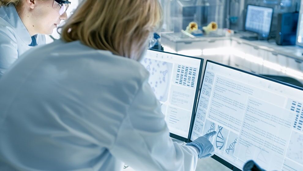 two lab researchers discuss dna information on screen in bioinformatics software