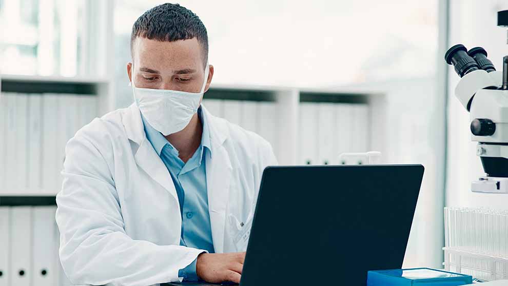researcher access clinical trial data management system on laptop seated at desk